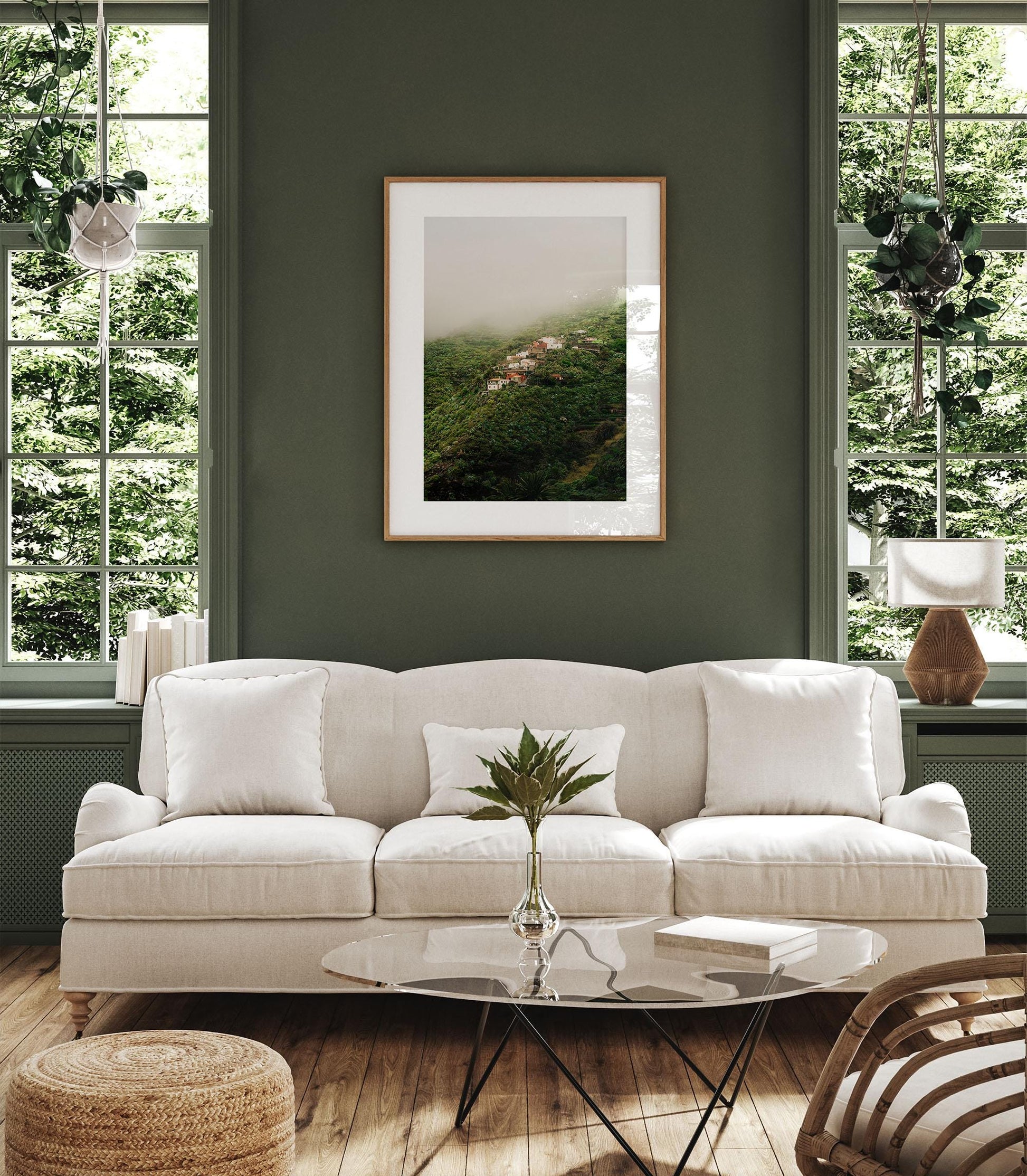 A cozy living room with Masca Mist sofa, glass coffee table, and large windows showing green trees outside.