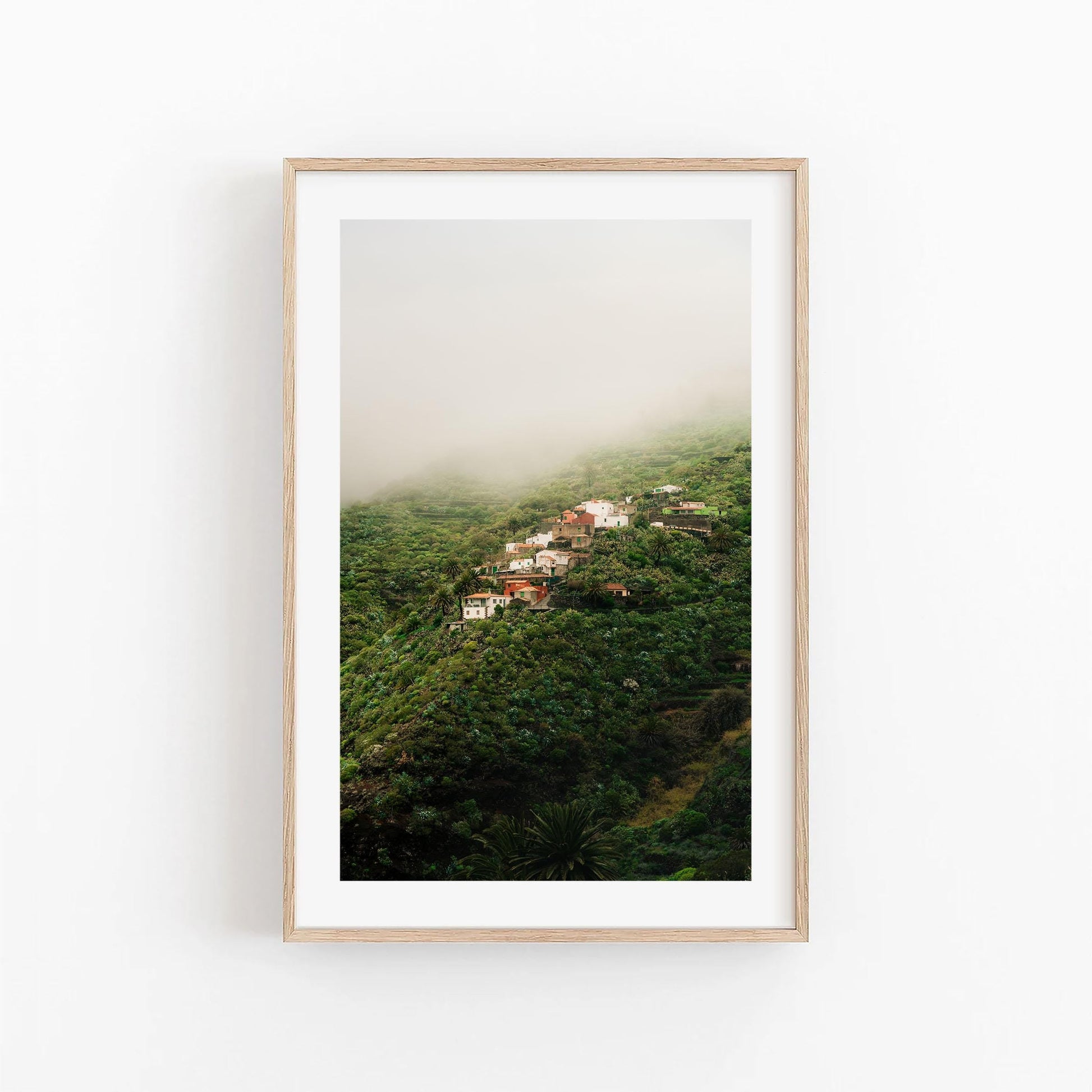 Masca Mist: Framed photo of houses on a lush green hillside surrounded by mist and fog.