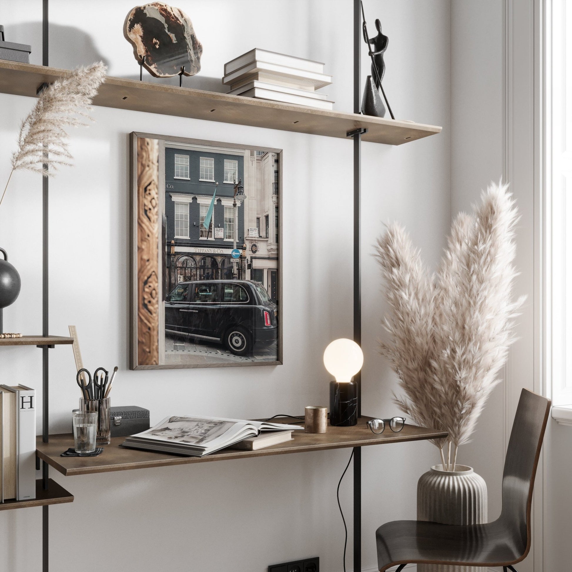 Minimalist home office with Mayfair Gild desk, plants, lamp, books, and window view reflecting a street scene in a mirror.