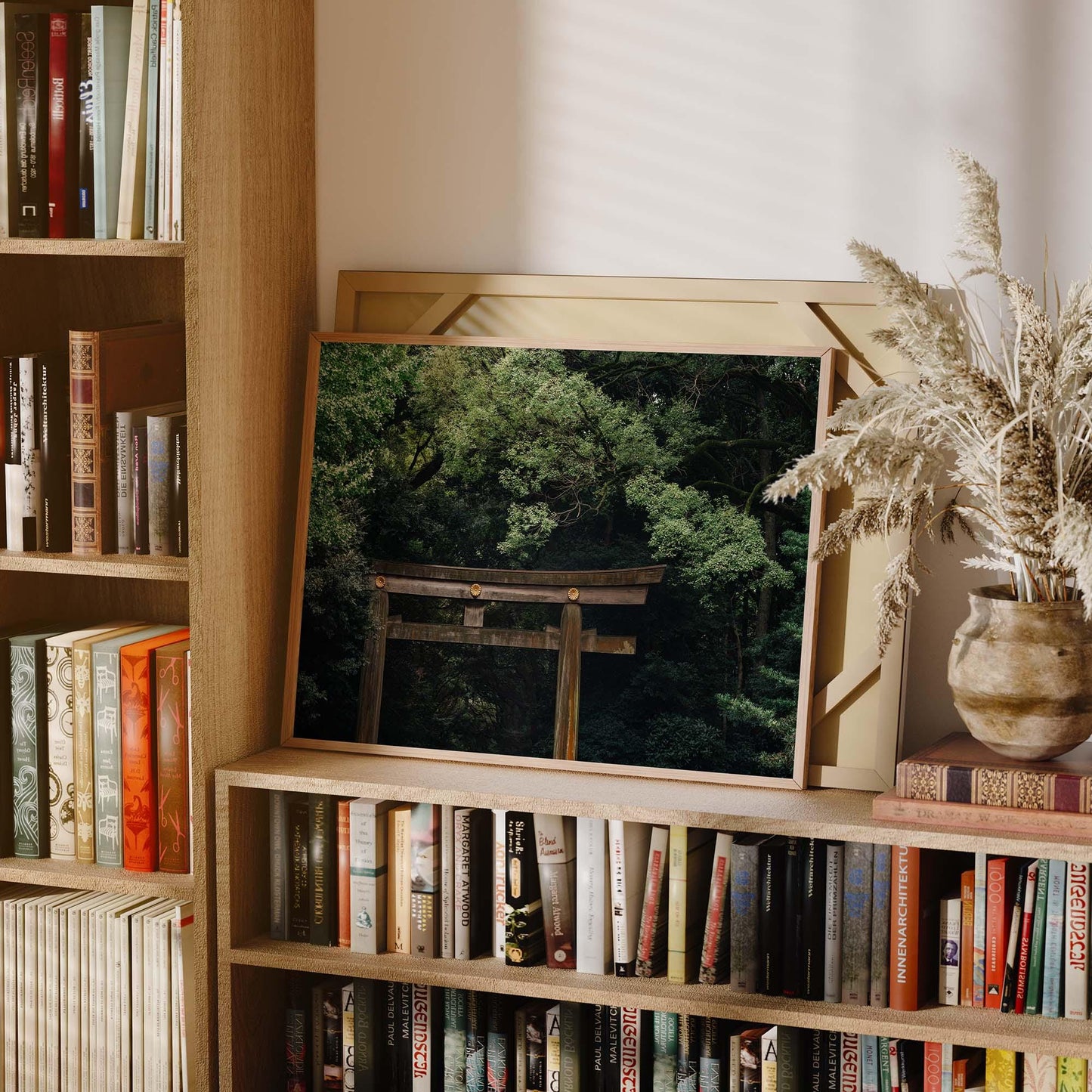 Framed photo of Meiji Jingu Shrine on a bookshelf, surrounded by books and a vase with dried grasses.