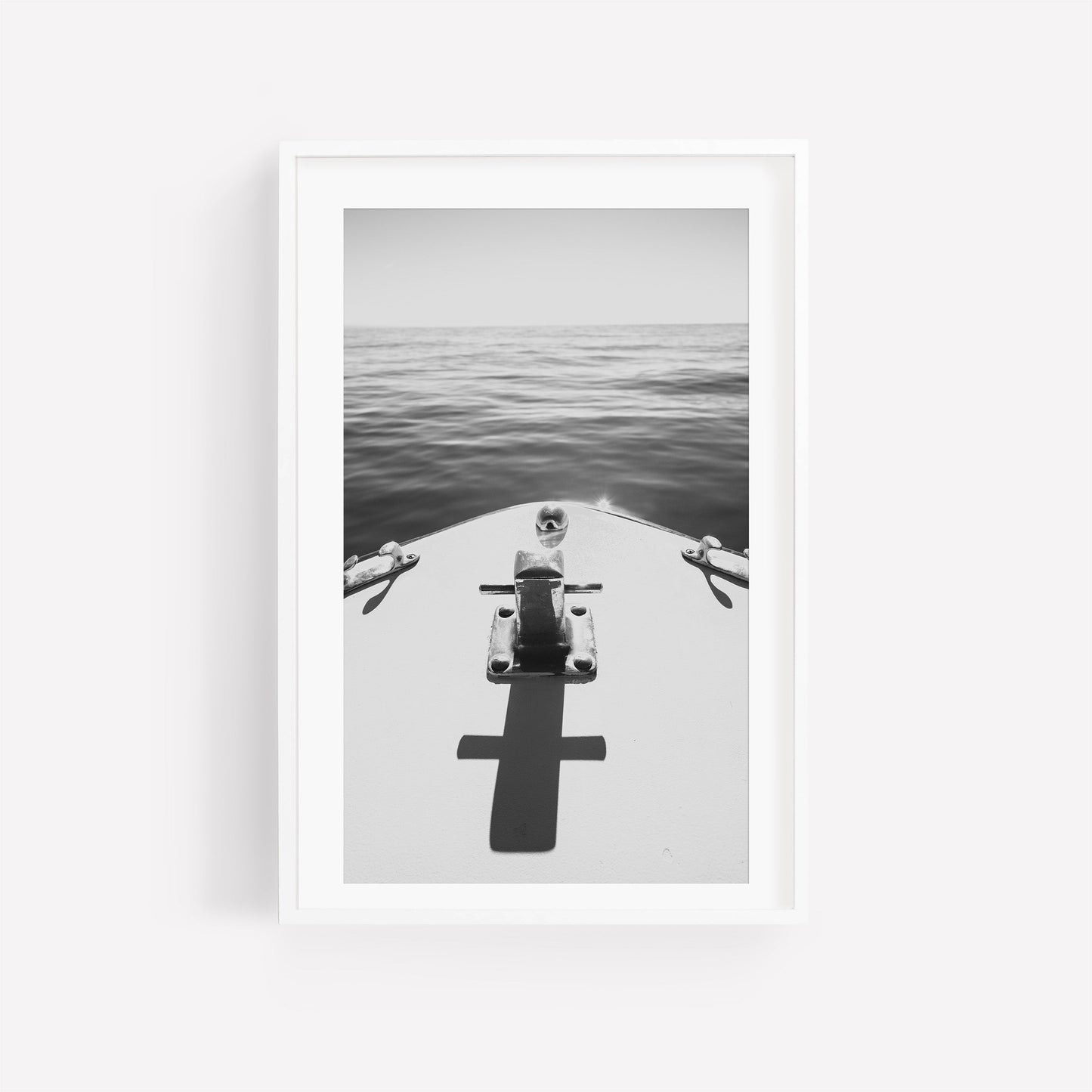 Midday Cruise Black and White: Photo of a boats bow with a cross shadow on calm sea, framed in white.