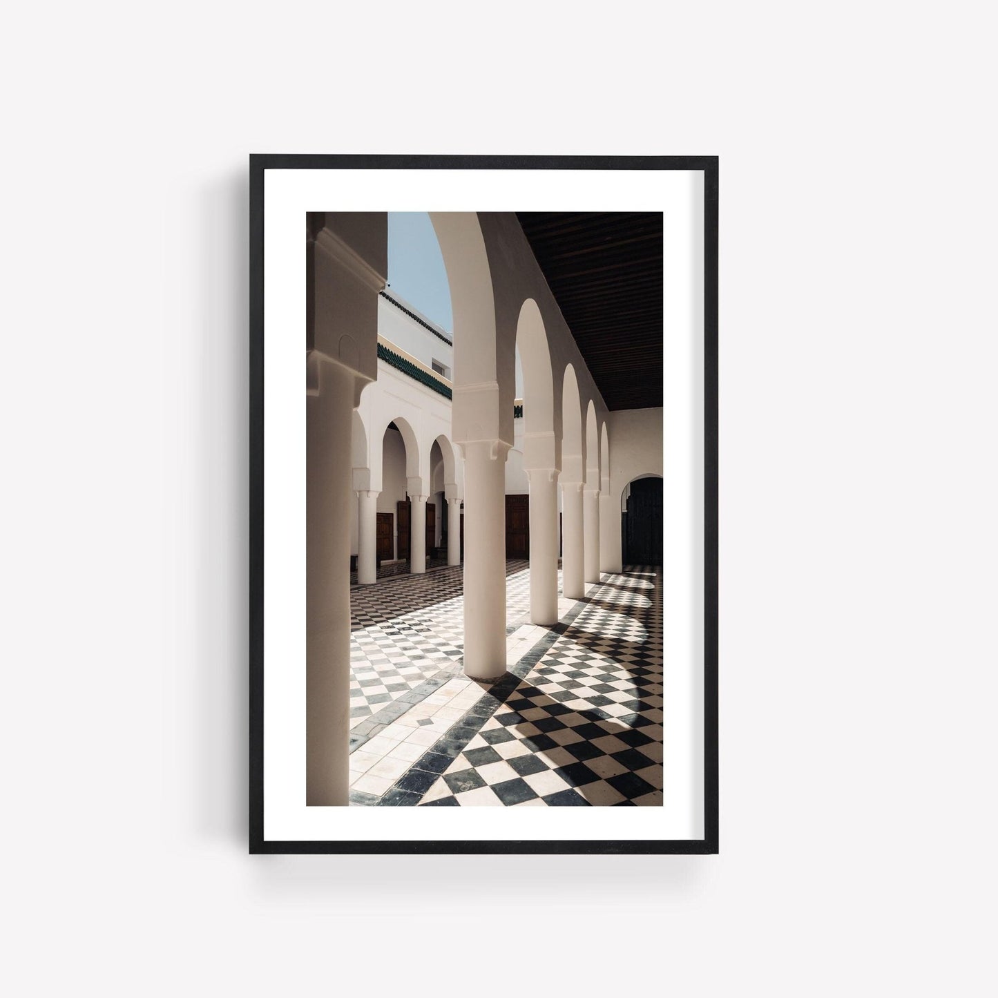 Framed photo titled Moroccan Architecture II of a sunlit corridor with arches and checkered black-and-white tiles.
