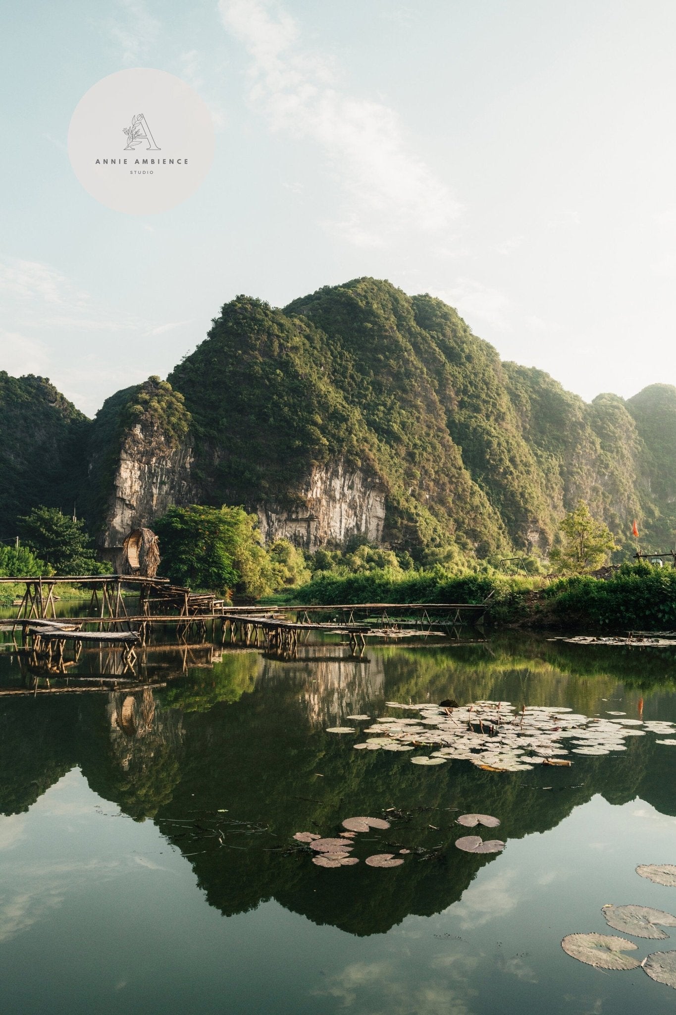 Scenic view in Natures Symmetry: mountain reflected in a calm lake with lily pads and a wooden bridge.