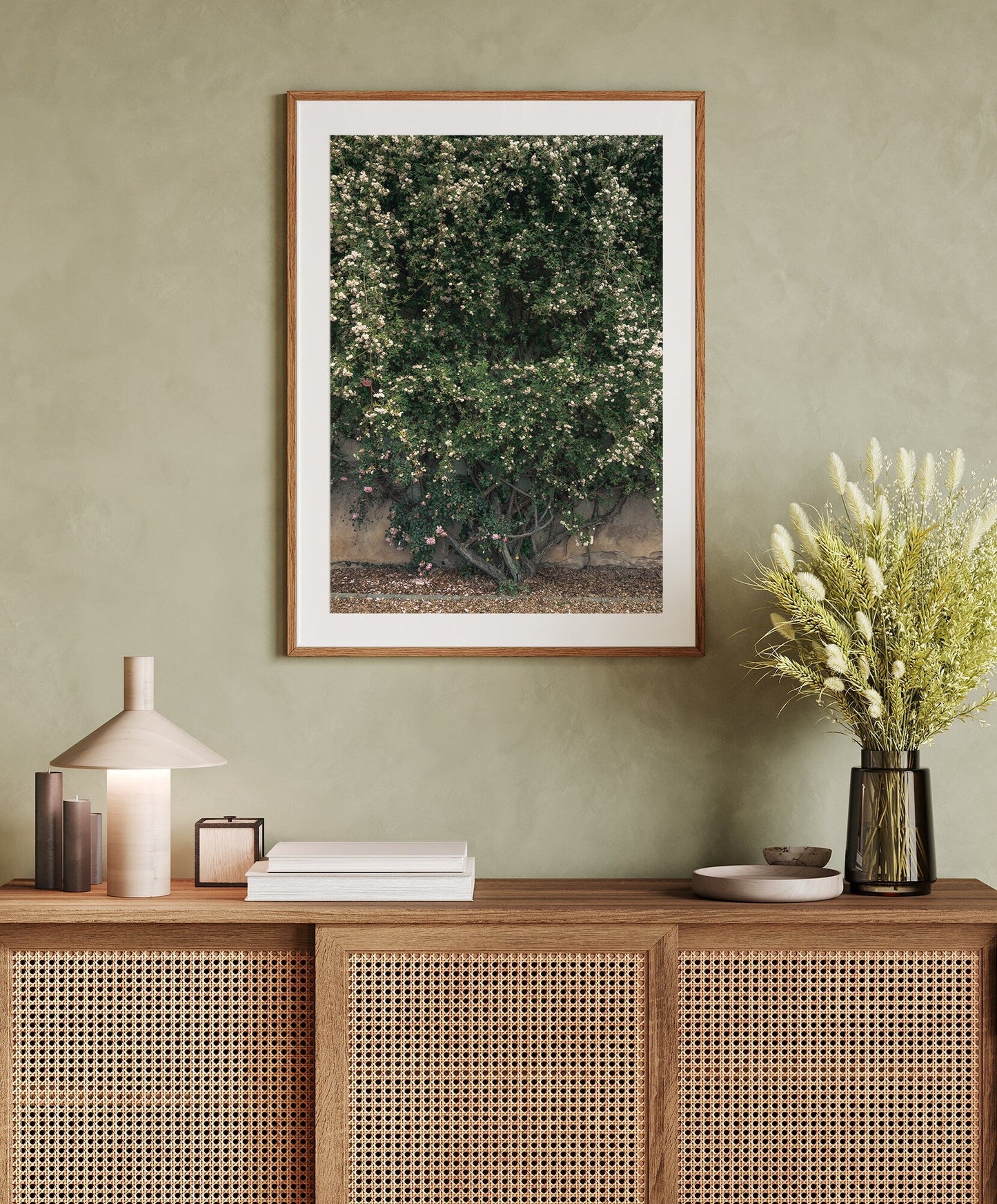 Natures Wall artwork on a green wall above a wooden console with books, a lamp, and a vase of flowers.
