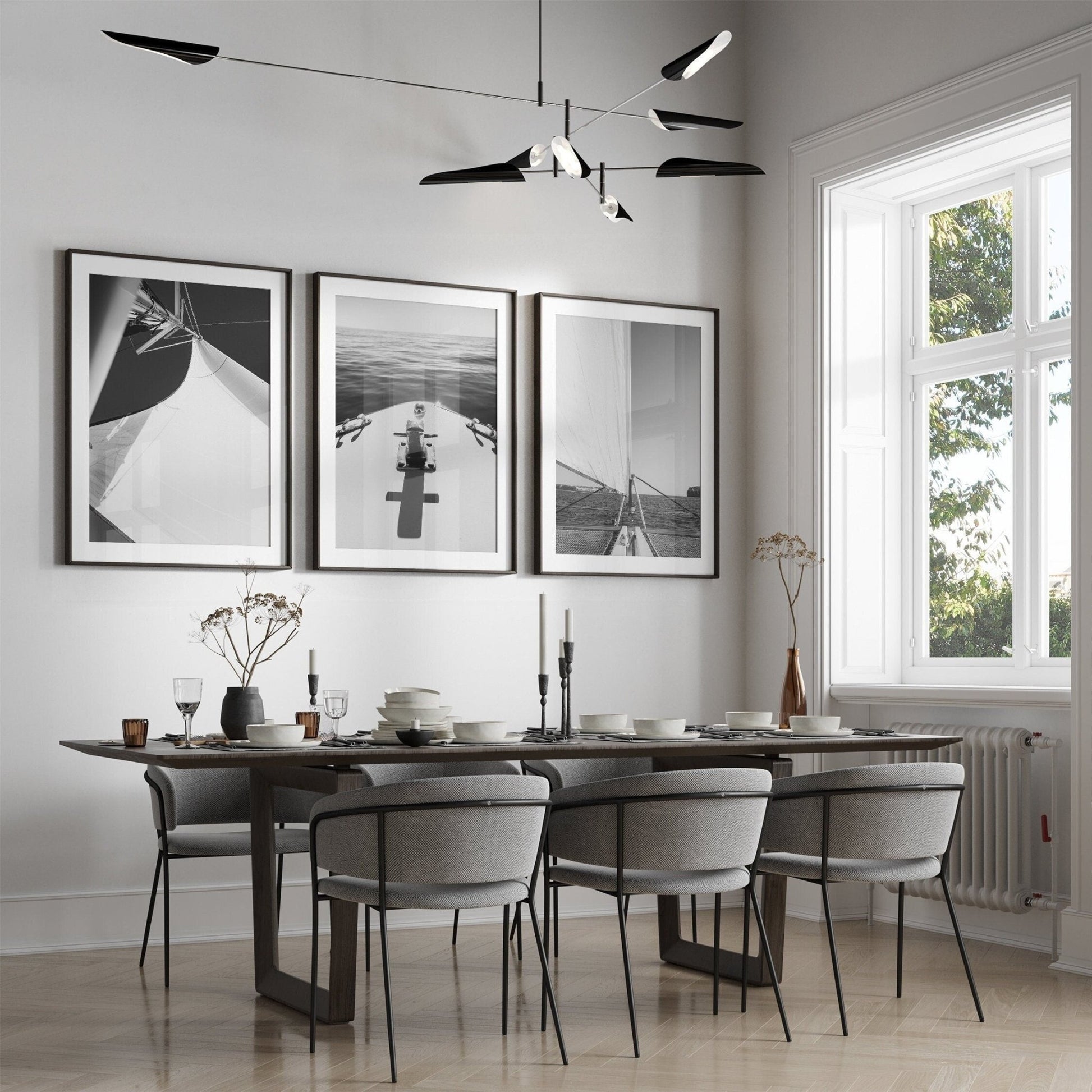 Modern dining room with a dark table, six chairs, and Nautical Elegance Black and White - Set of 3 wall art.