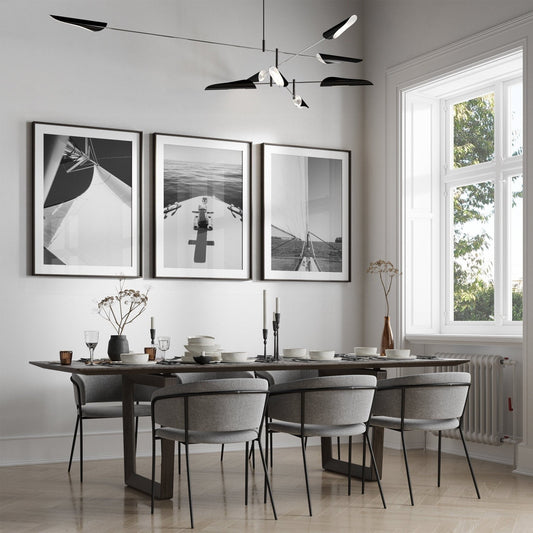 Modern dining room with a dark table, six chairs, and Nautical Elegance Black and White - Set of 3 wall art.