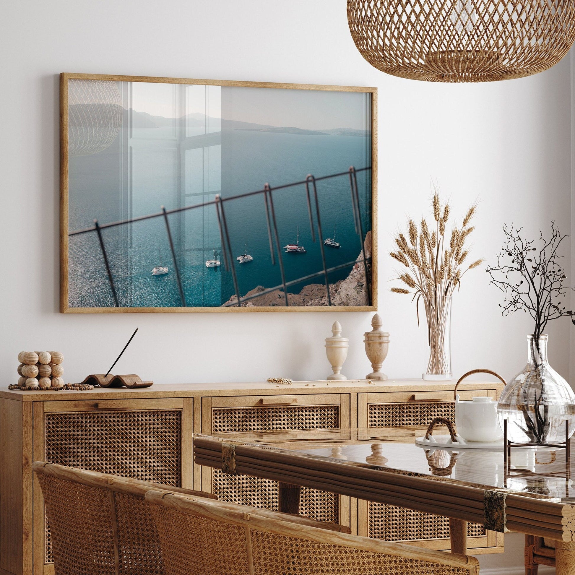 Dining room with Nautical Formation sideboard, rattan chairs, coastal photo, dried plants, and pottery on display.