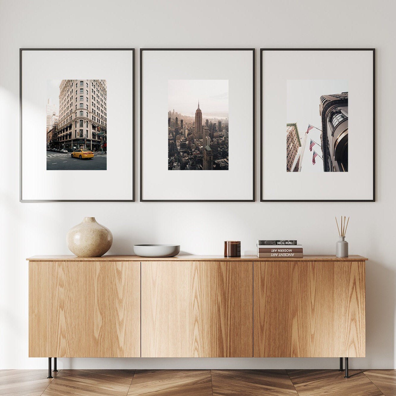 Wooden sideboard with decor underneath the NYC - Set of 3 framed cityscape photos.