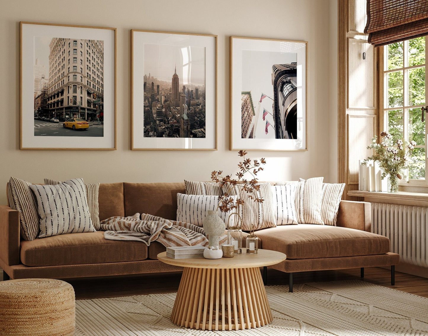 Cozy living room with beige sofa, patterned cushions, round wooden table, and NYC - Set of 3 photos on the wall.