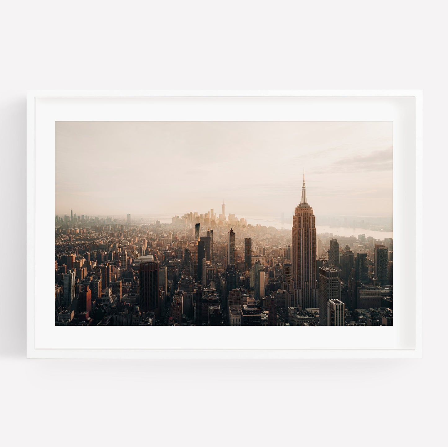 Aerial view of NYC skyline in black and white, featuring the Empire State Building at sunset among tall buildings.