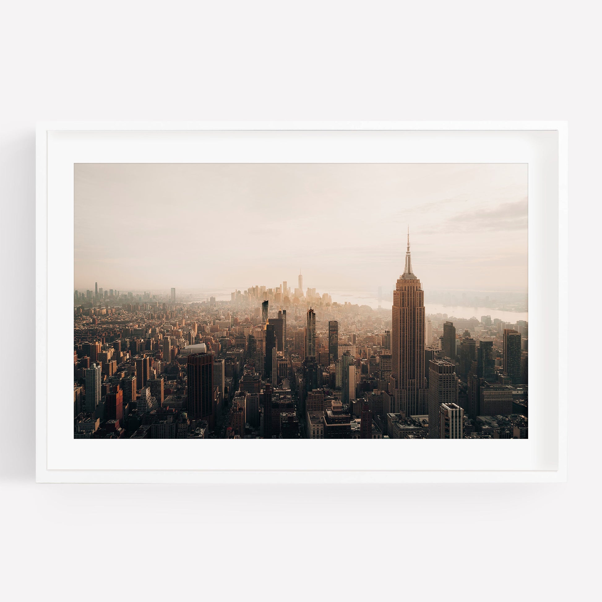 Aerial view of NYC skyline in black and white, featuring the Empire State Building at sunset among tall buildings.
