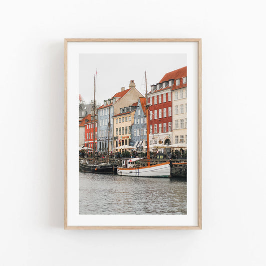 Framed photo of colorful buildings and boats, likely Nyhavn in Copenhagen, against a white background. Product: Nyhavn Canal.