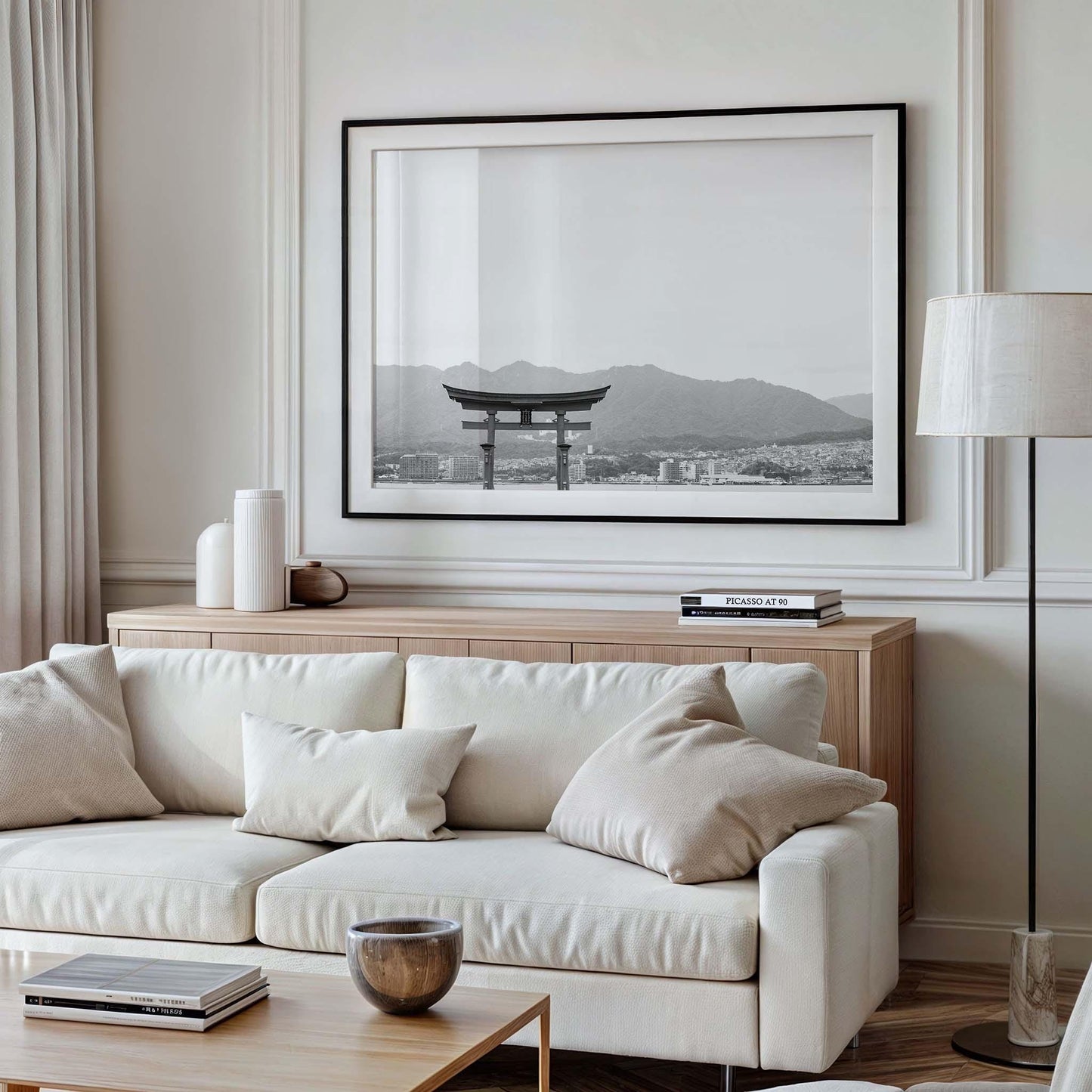 Minimalist living room with a white sofa, neutral pillows, floor lamp, wood accents, and O-Torii Gate Black and White art.