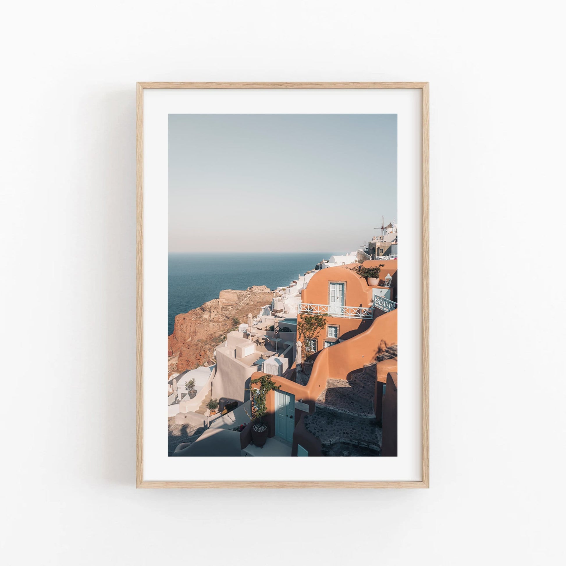 Framed art print Oia of a coastal village with white and terracotta buildings by the sea.