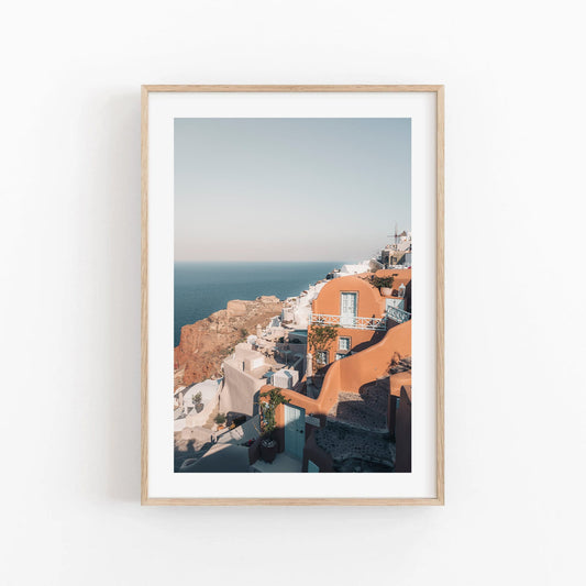 Framed art print Oia of a coastal village with white and terracotta buildings by the sea.