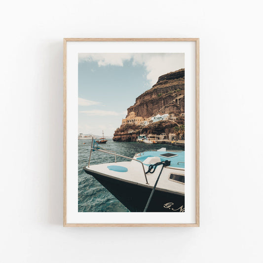Framed photo Old Port Fira featuring a coastal town, boat in foreground, and cliffside backdrop.
