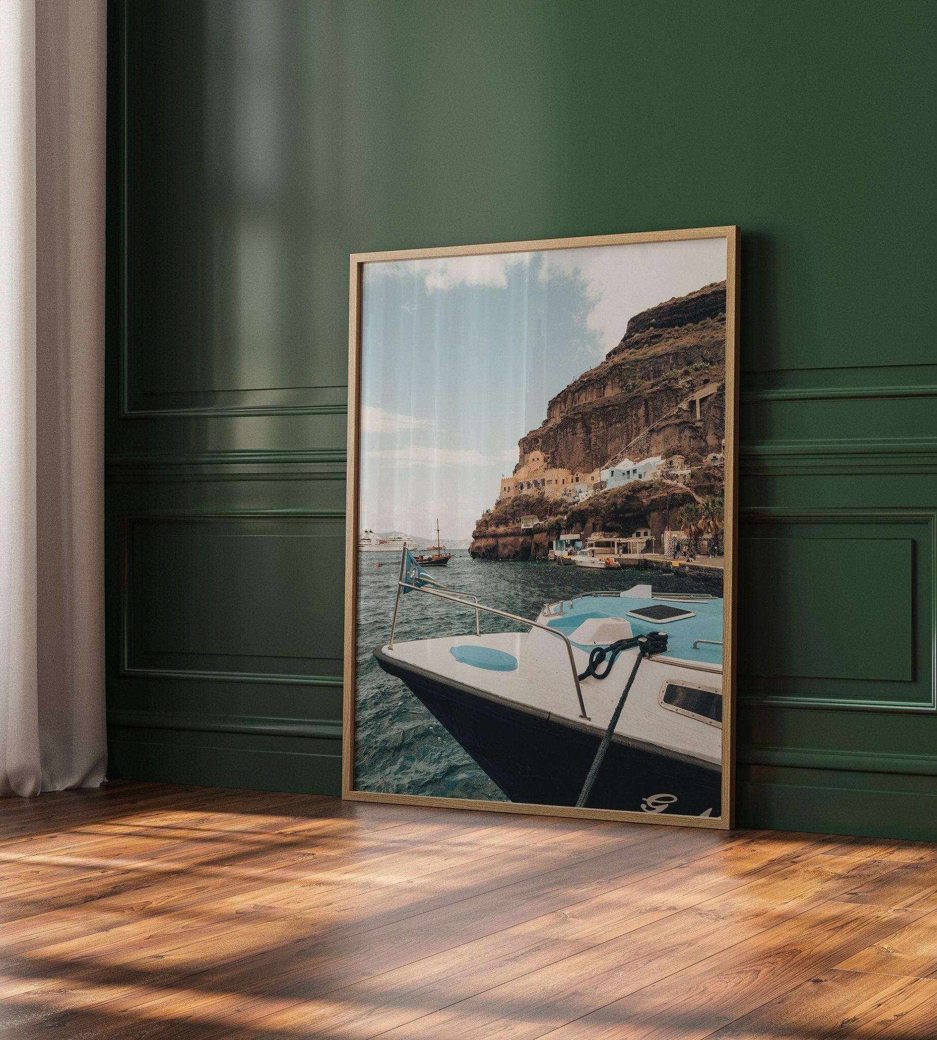 Old Port Fira photo of a boat and cliffs, leaning on a green paneled wall over a wooden floor.