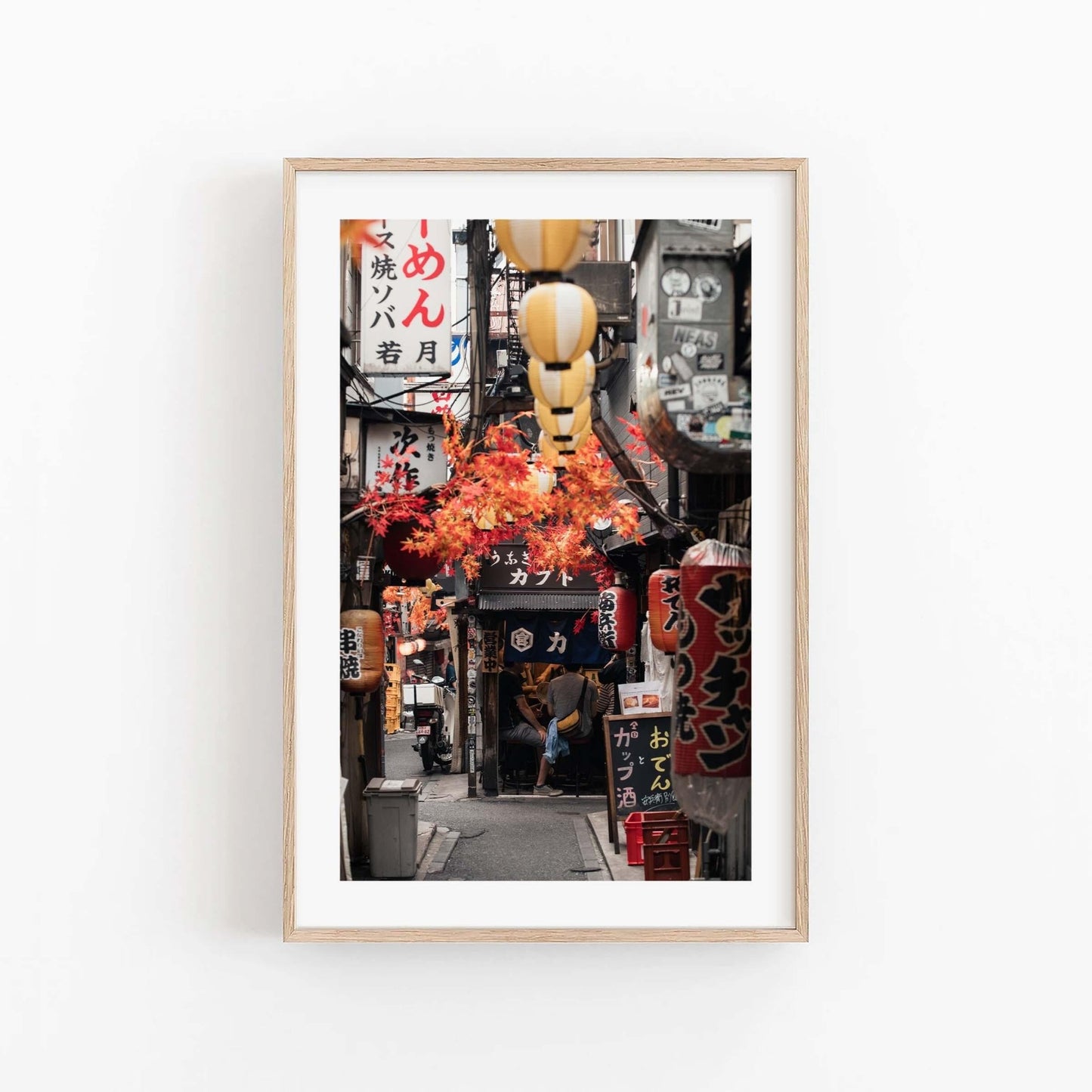 Framed photo titled Omoide Yokocho, depicting a narrow Tokyo street adorned with lanterns and vibrant signs.