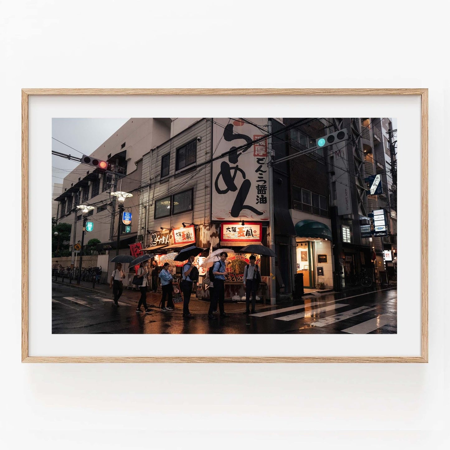 Osaka Drizzle: A framed photo capturing a rainy Japanese street scene with people holding umbrellas in front of a ramen shop.