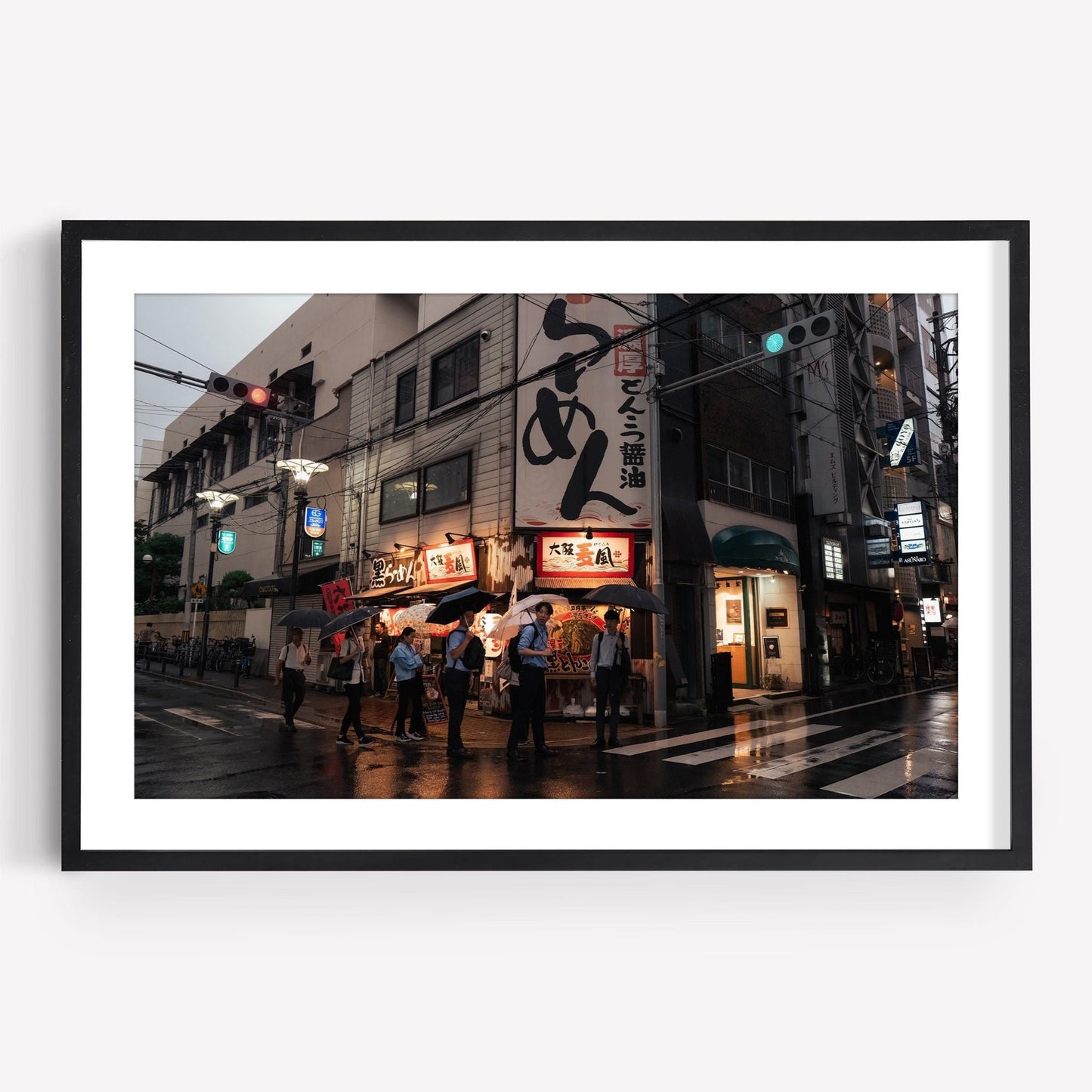 Framed photograph titled Osaka Drizzle depicting people standing outside a ramen shop on a rainy street at dusk.
