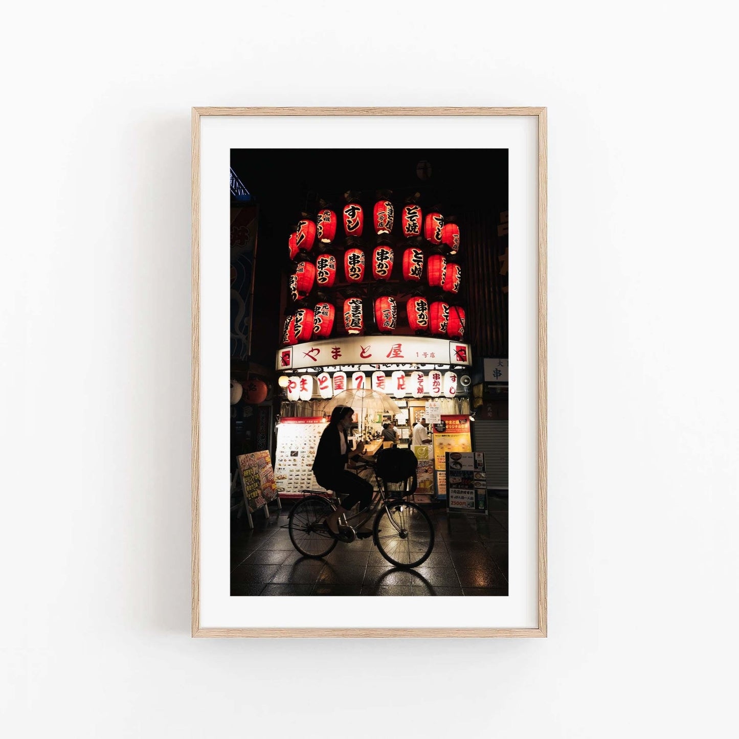 An Osaka Lantern Biker rides through a dimly lit street under bright red lanterns at night.
