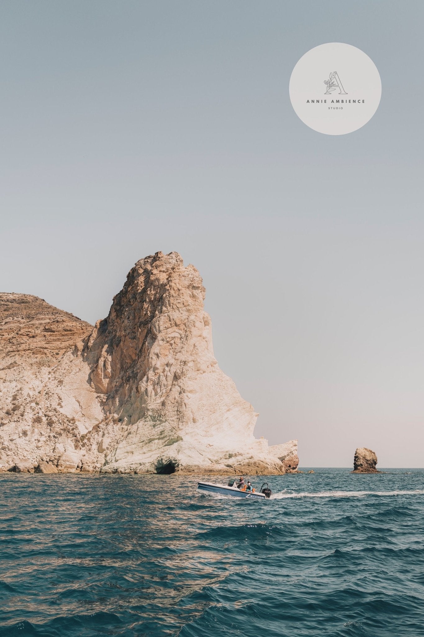 The Perissa - Set of 3 showcases a small boat by rocky cliffs in calm blue ocean waters under a clear sky.