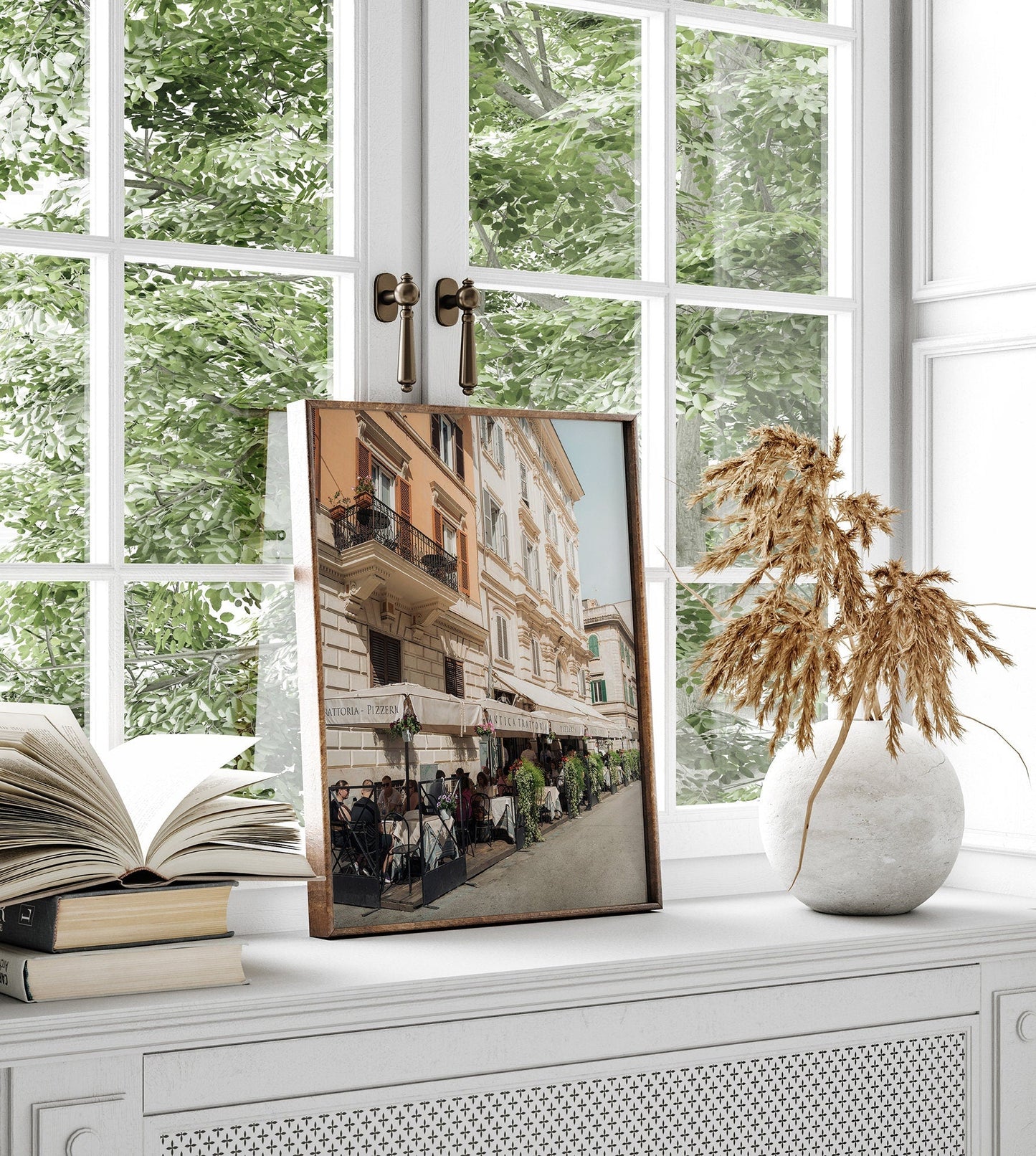 Framed Pizzeria photo on a windowsill, with dried plants in a vase and open books nearby.
