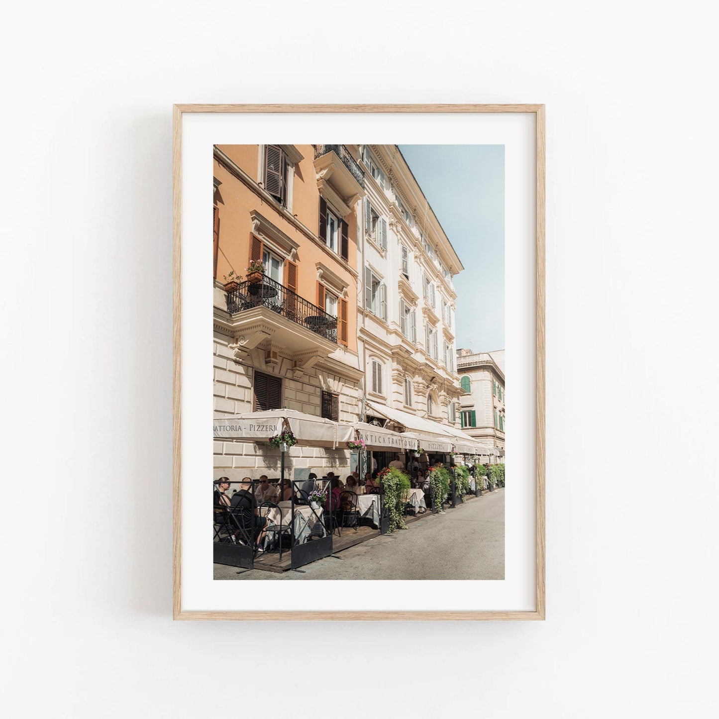 Framed photo of a lively street cafe with diners under umbrellas.