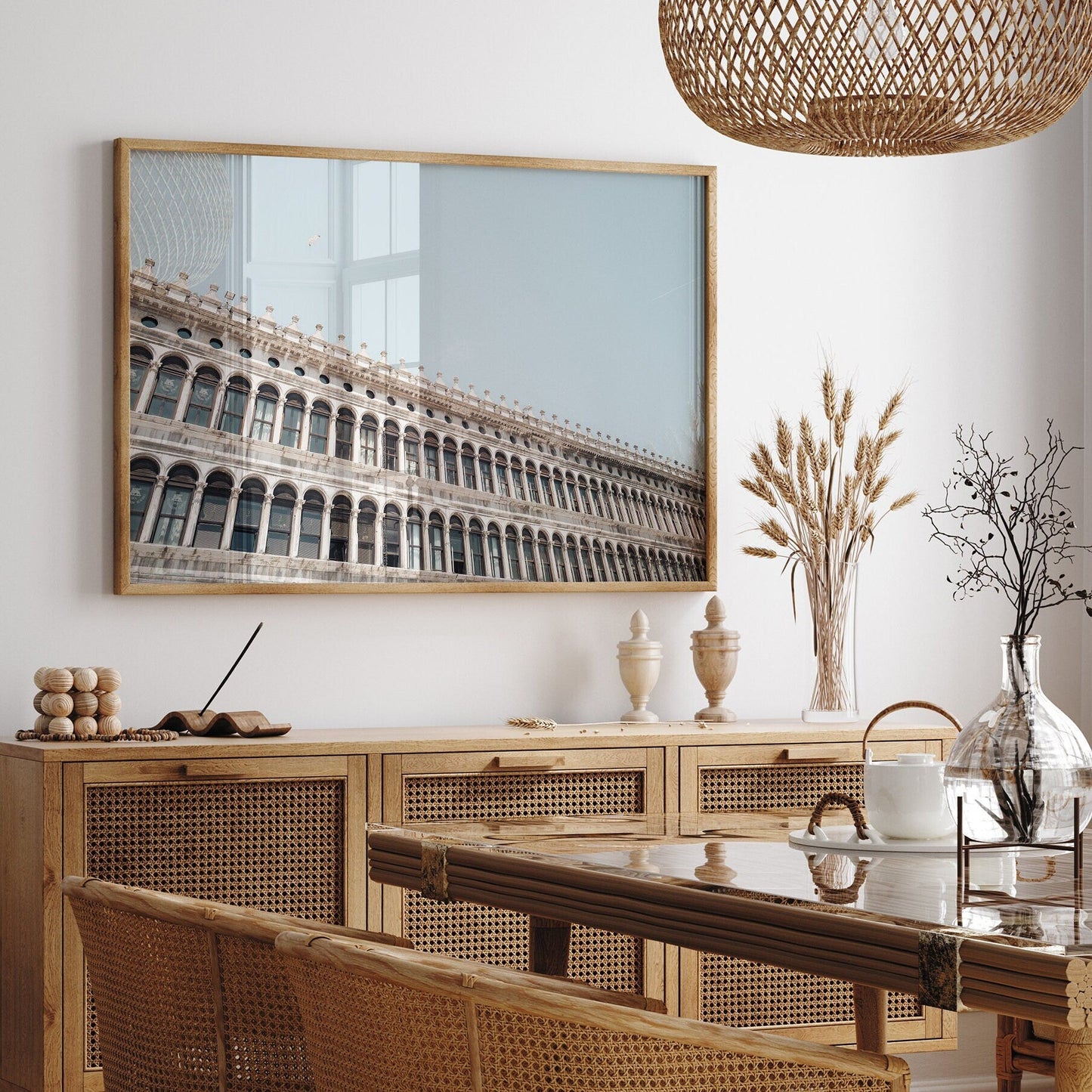 Dining room with wicker furniture, the Procuratie Vecchie photo, and vases on a wooden sideboard.