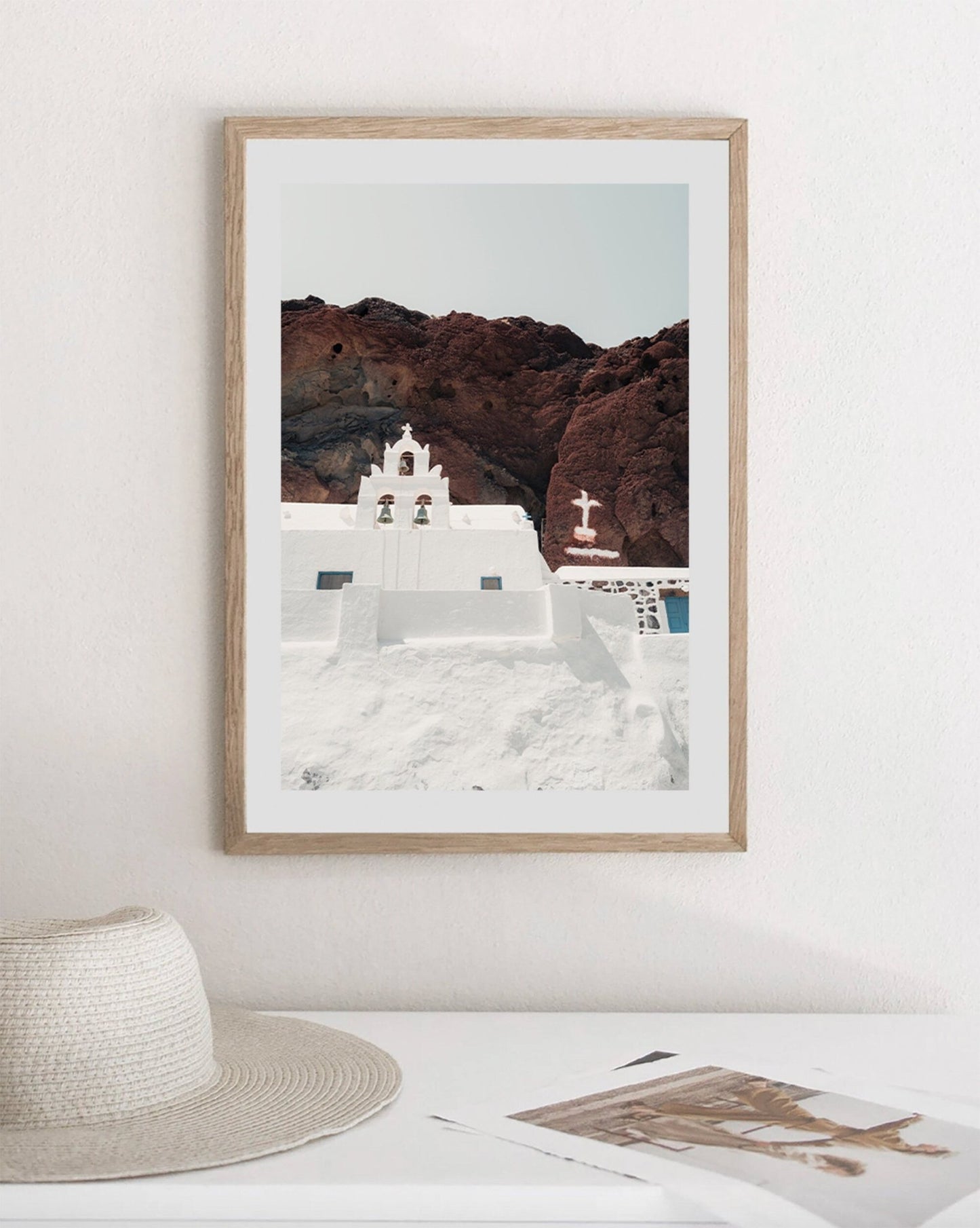 The Red Beach Church photo depicts a white building on a rocky cliff, displayed above a desk with papers and a hat.