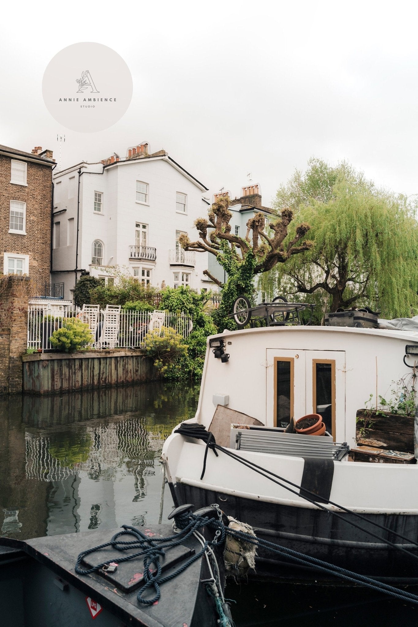 Regents Canal II: houseboats moored on a canal with trees and houses in the background under a cloudy sky.