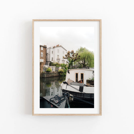 Framed photo titled Regents Canal II depicting a houseboat with surrounding houses and greenery.