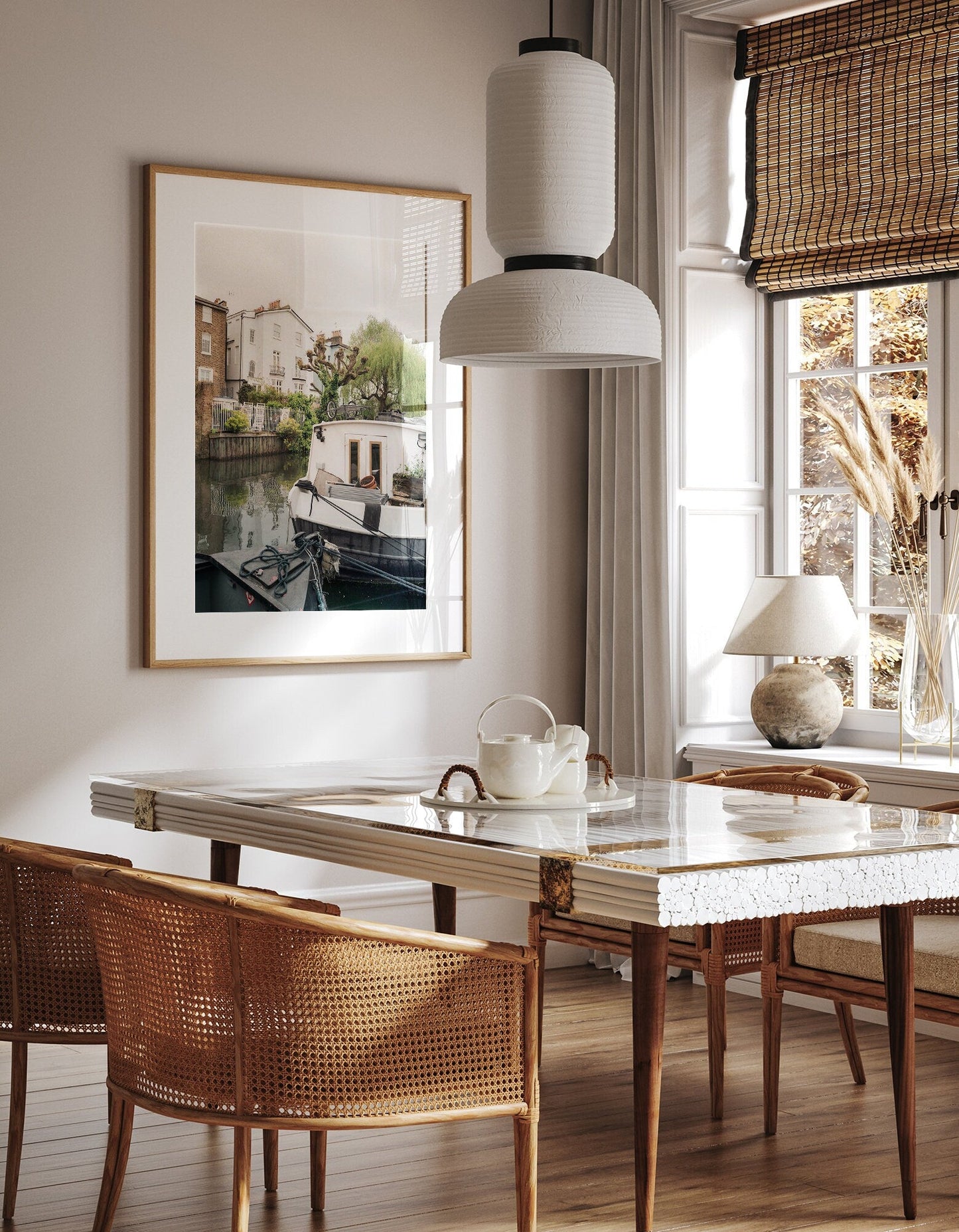 A cozy dining area featuring a marble table, wicker chairs, pendant light, and a large framed Regents Canal II photo.