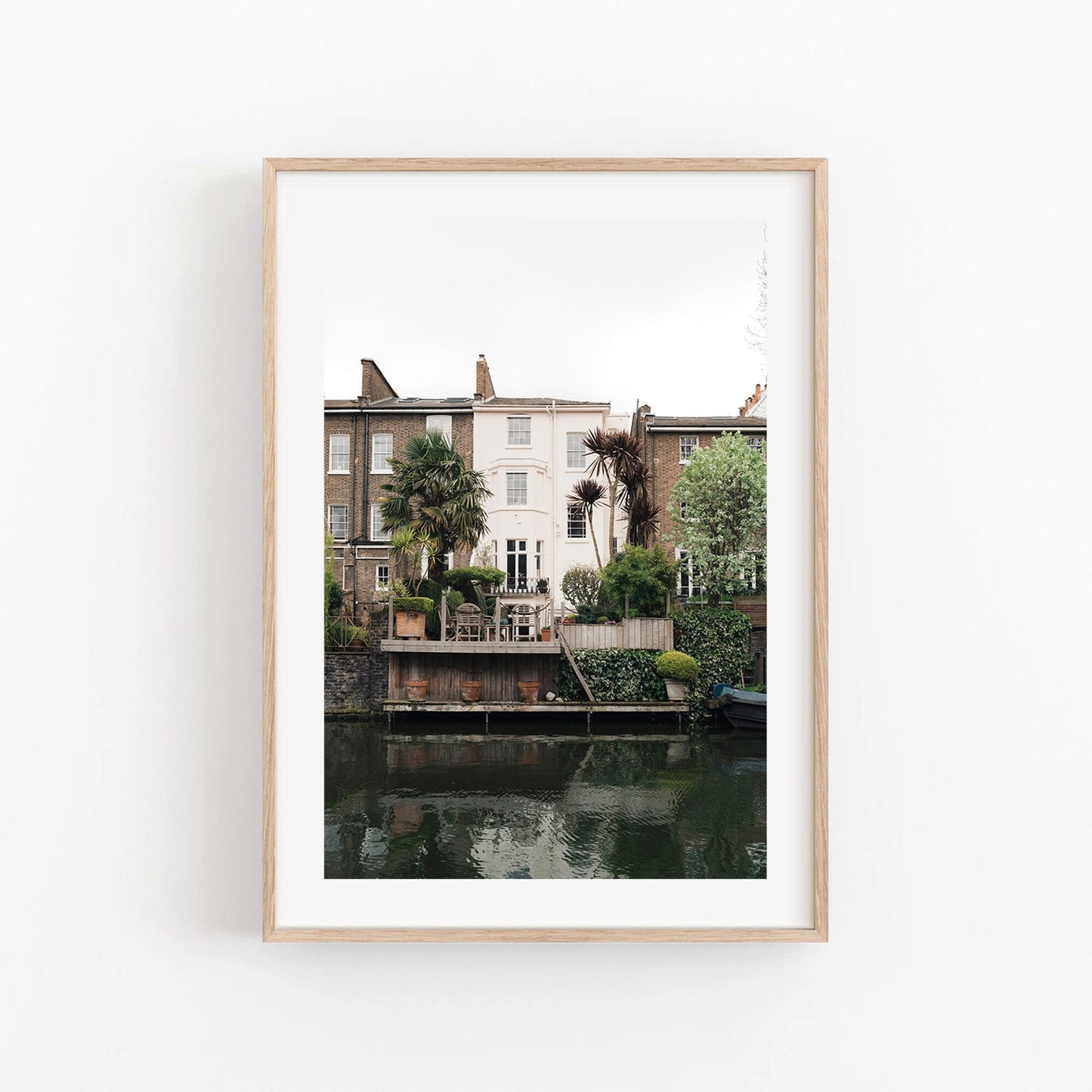 Framed photo of Regents Canal house with palm trees and greenery reflected in the water on a white background.