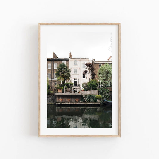Framed photo of Regents Canal house with palm trees and greenery reflected in the water on a white background.