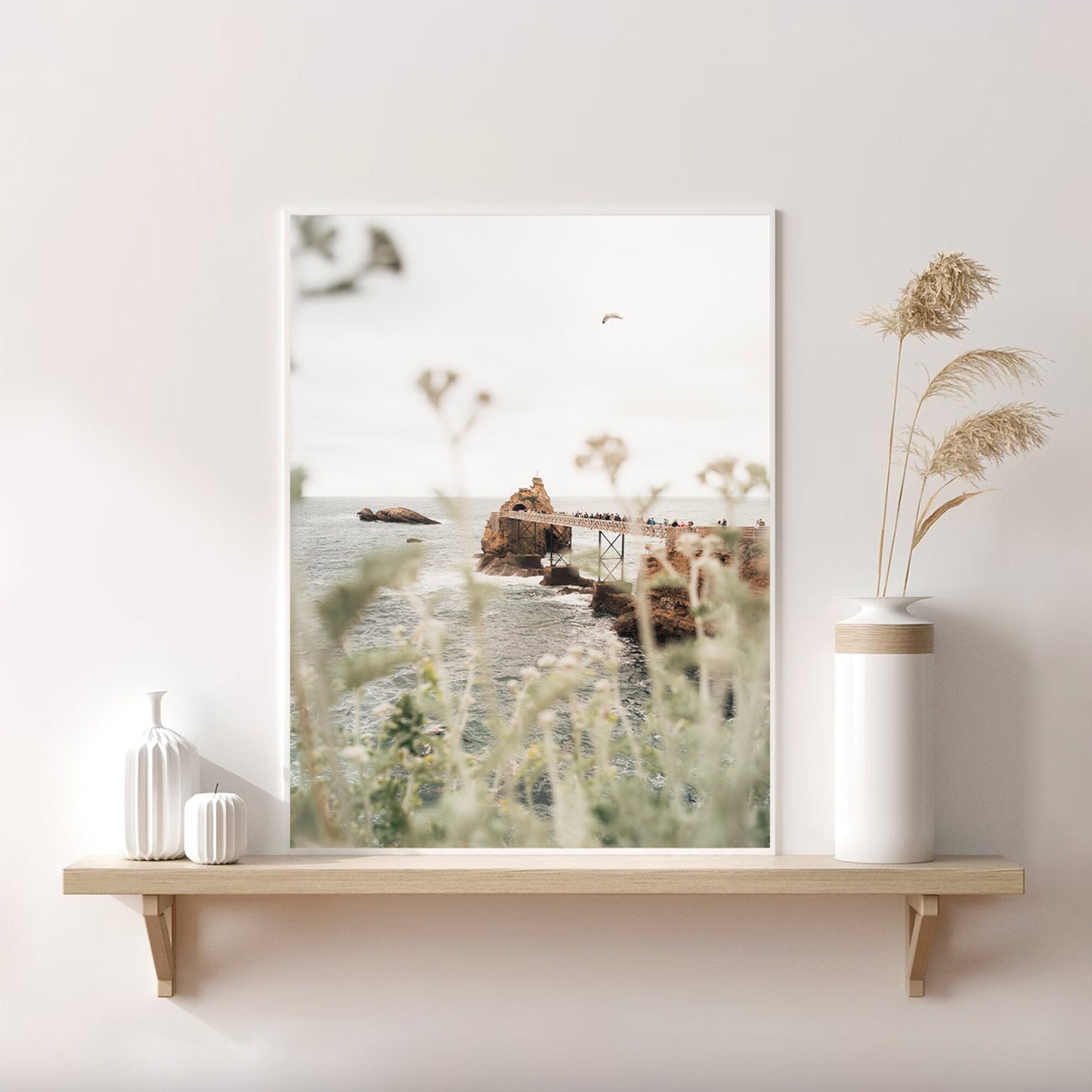 The Roche de le Vierge photo, framed on a shelf with vases, showcases wild grasses and distant cliffs.
