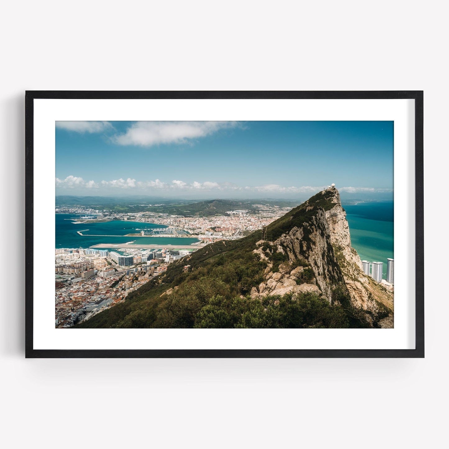 Framed photo titled Rock of Gibraltar features a rocky promontory with a city, water, and hills under a blue sky.