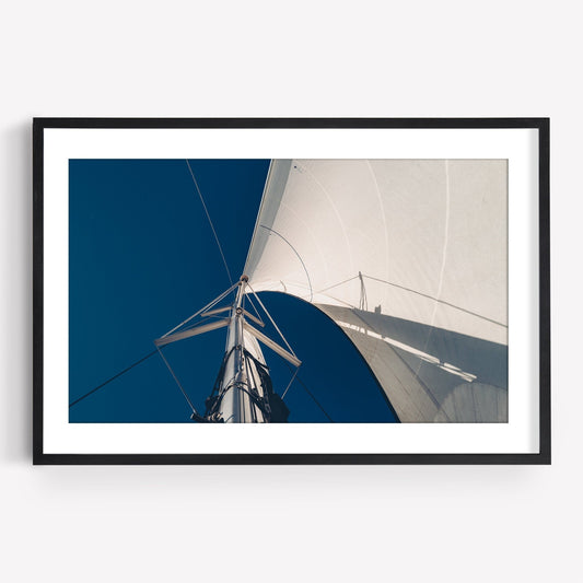 Framed image Sailing Bliss captures a sailboat mast and sail against a deep blue sky from below.