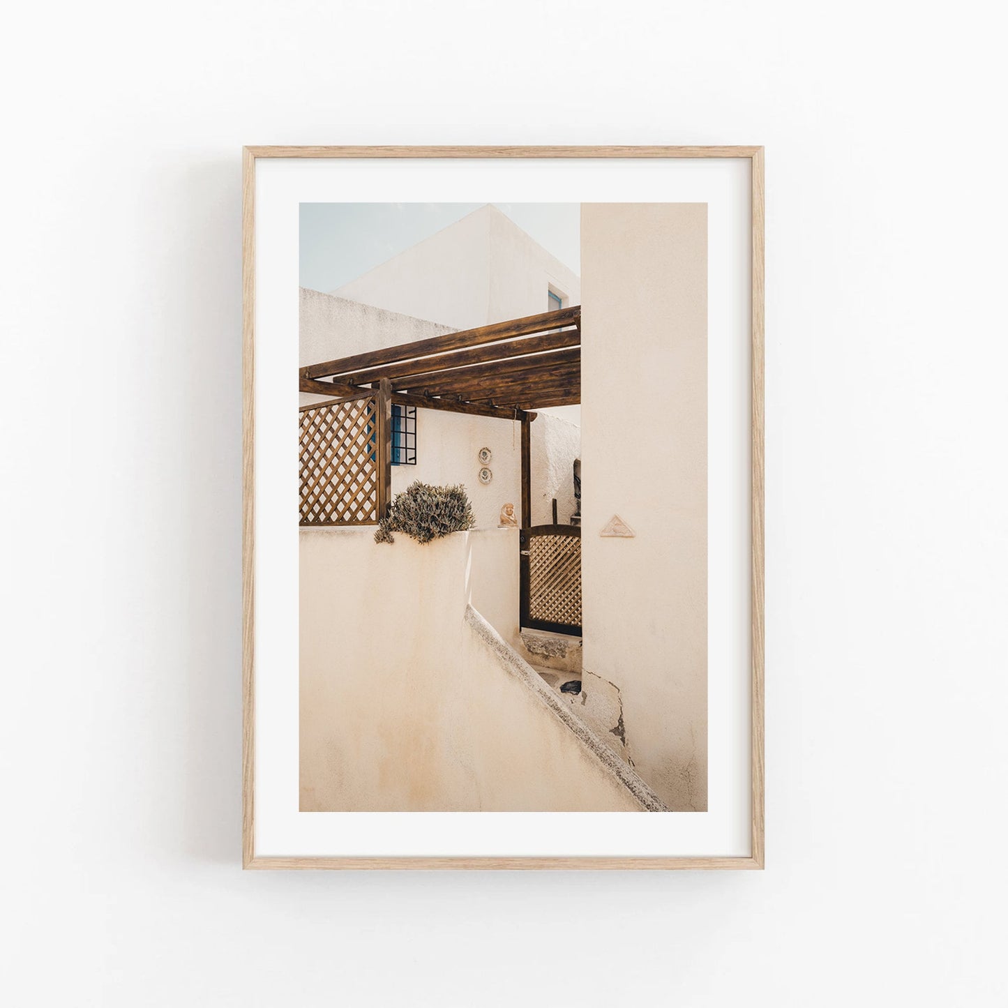 Sand Serenity: A sunlit Mediterranean patio with beige walls and a wooden pergola, beautifully framed.