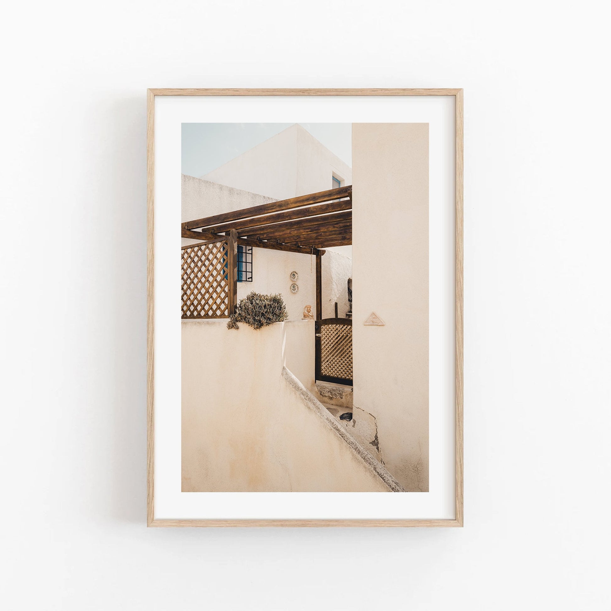 Sand Serenity: A sunlit Mediterranean patio with beige walls and a wooden pergola, beautifully framed.