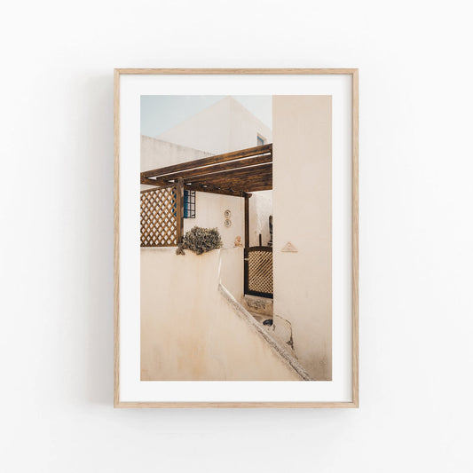 Sand Serenity: A sunlit Mediterranean patio with beige walls and a wooden pergola, beautifully framed.