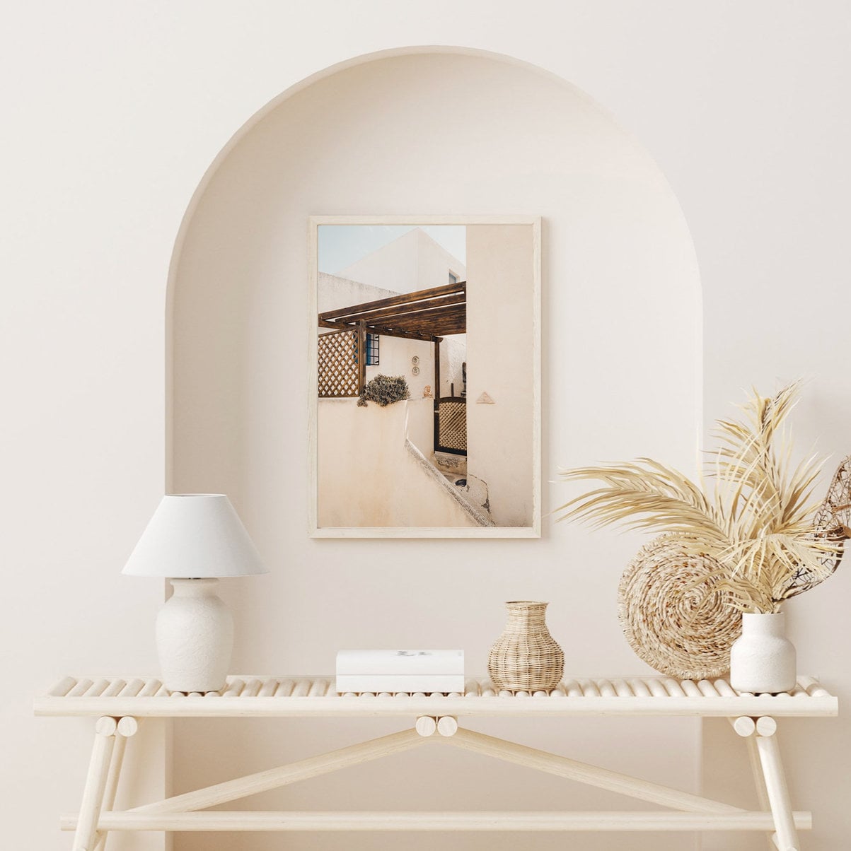 Sand Serenity: Minimalist decor featuring a lamp, vases, and framed photo on a wooden console under an archway.