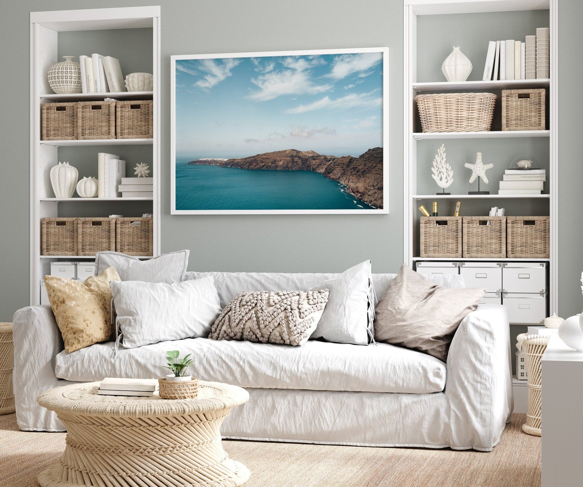 A cozy living room with a white sofa and coastal decor features the Santorini Mountain landscape photo on the wall.