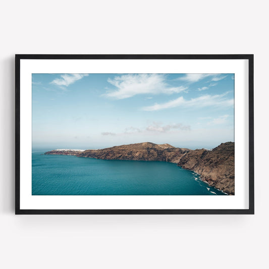 Framed photo titled Santorini Mountain features a rocky coastline, clear blue waters, and a partly cloudy sky.