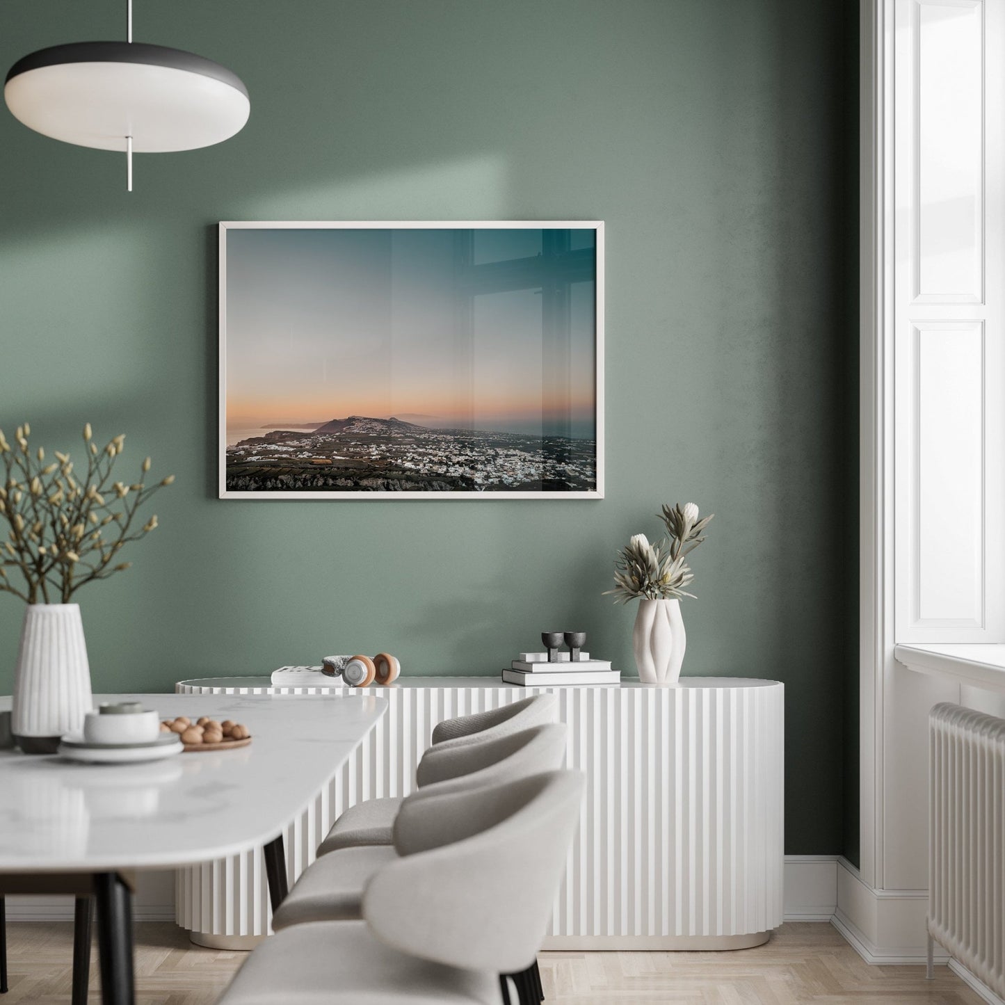 Modern dining room featuring Santorinis Glow photo, green walls, white furniture, and minimalist decor.