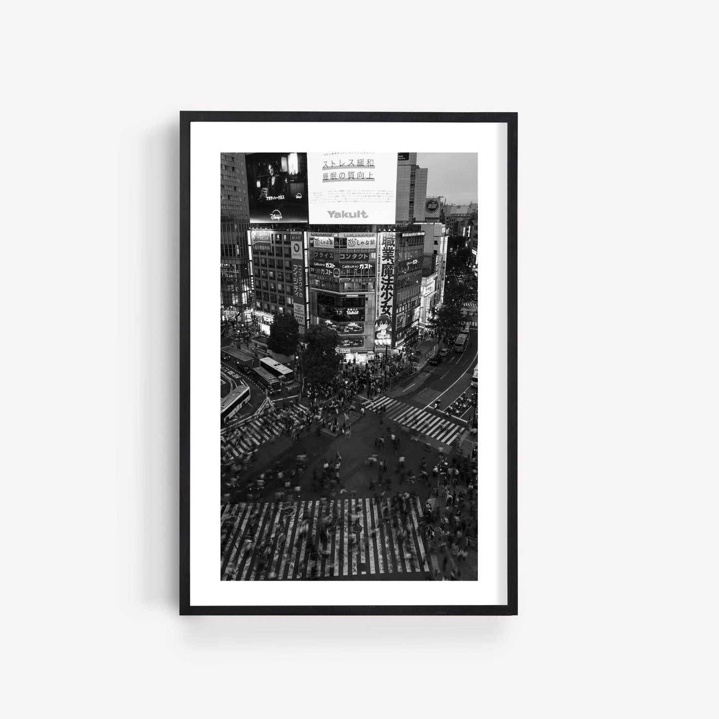 Shibuya Crossing Black and White framed photo of a bustling city intersection with crowds and bright signs on a white wall.