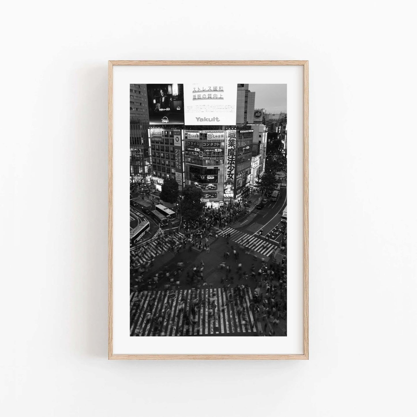 Framed Shibuya Crossing Black and White photo of a bustling city intersection with pedestrians and bright billboards.