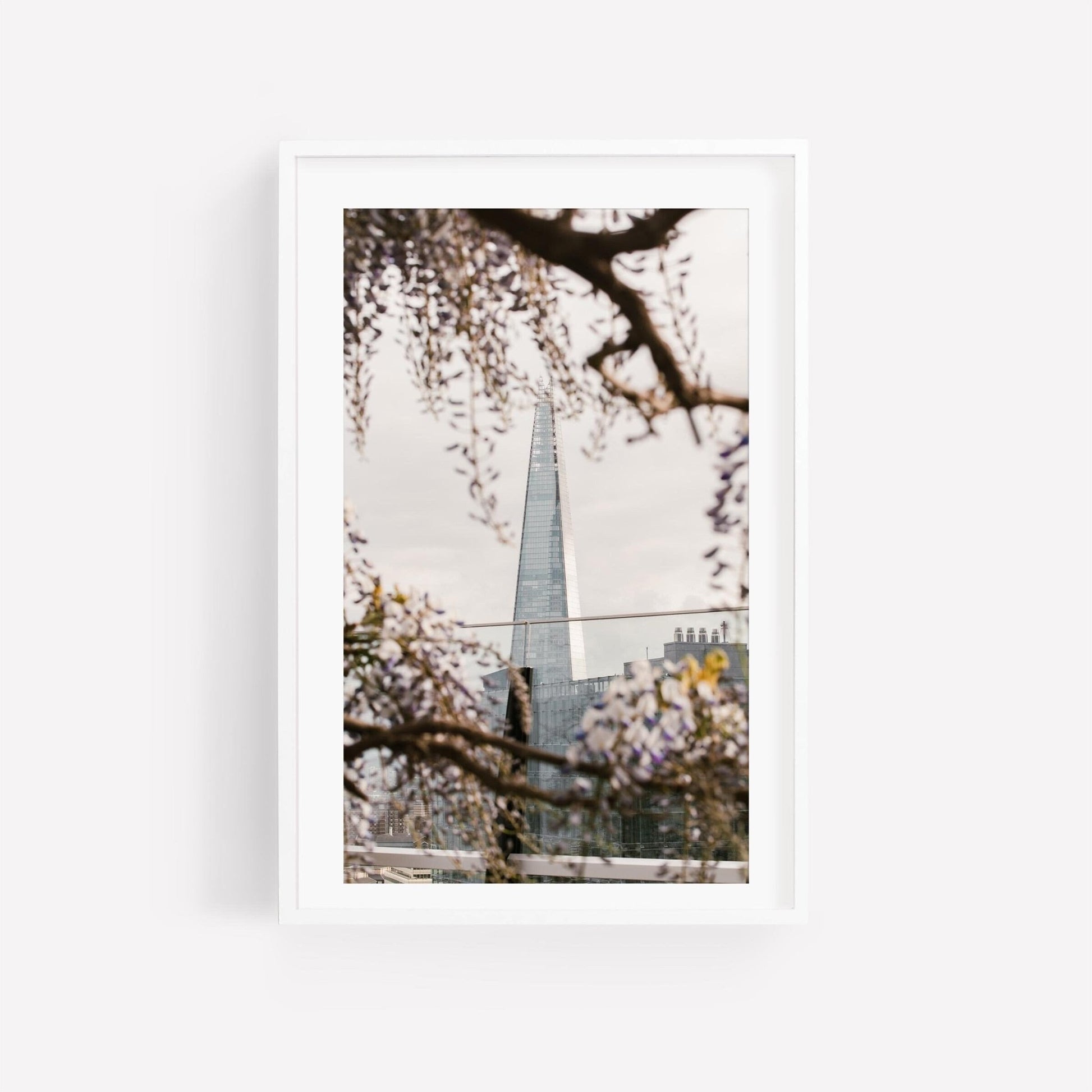 Springtime Shard: Framed photo of a pointed building through blooming branches against a cloudy sky.