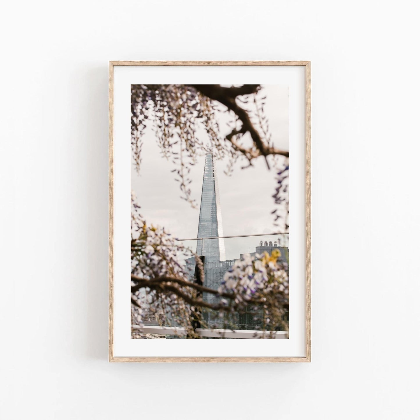Framed Springtime Shard photo of a tall glass building through flowering branches on a white wall.
