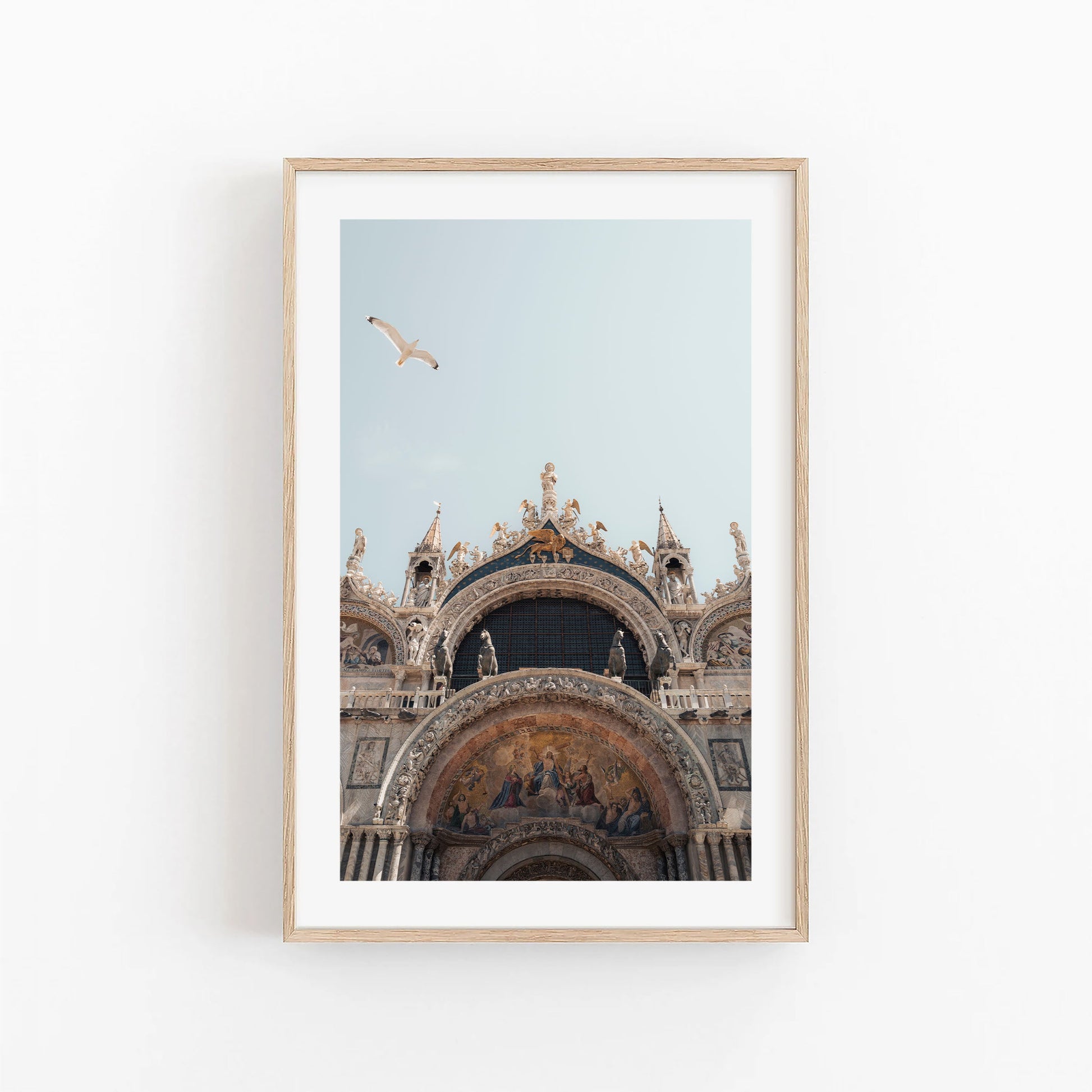 Framed photo of St. Marks Basilica with a seagull soaring above against a clear blue sky.